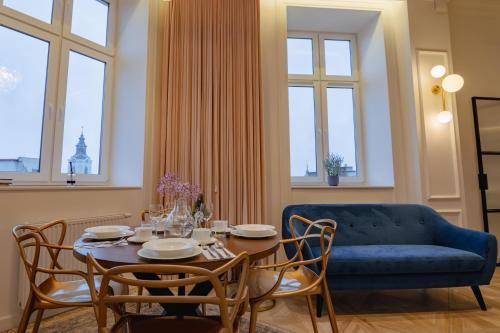 uma sala de estar com uma mesa e um sofá azul em Urso Apartament Premium em Przemyśl
