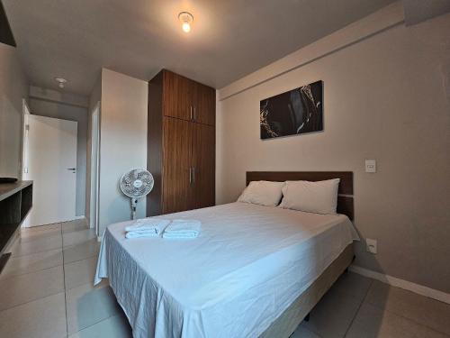 a bedroom with a large white bed with a fan at AP encantador na Praia do Forte! Porto Azul (106) in Cabo Frio