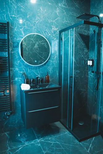 La salle de bains bleue est pourvue d'un lavabo et d'une douche. dans l'établissement Villa37, à Limoges