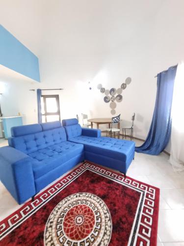 a blue couch in a living room with a red rug at VINCE SALY 3 in Sali Nianiaral