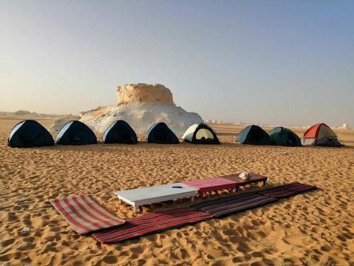 un grupo de tiendas en el desierto con una mesa y un colchón en White desert & Black desert camb en Qasr Al Farafirah