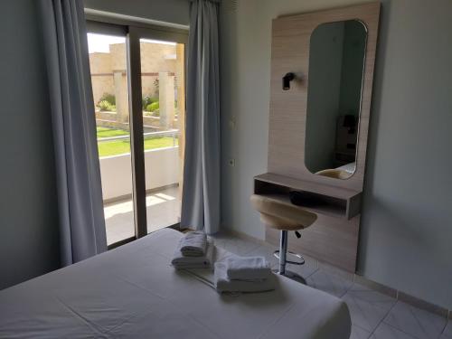 een slaapkamer met een bed met een spiegel en een stoel bij Viglia Beach Apartments in Kissamos
