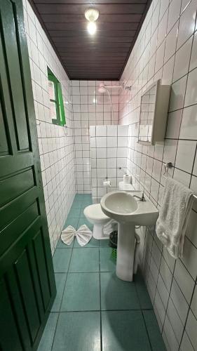 a bathroom with a white sink and a toilet at Suítes Casa Rosada in Ubatuba