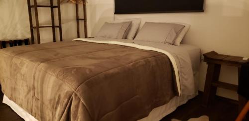 a bedroom with a large bed with a brown comforter at The Guest House hostel in Balneário Gaivotas