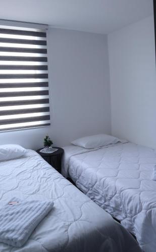 two twin beds in a bedroom with a window at TOCANCIPÁ, Increíble, Hermoso y Moderno APARTAMENTO COMPLETO! in Tocancipá