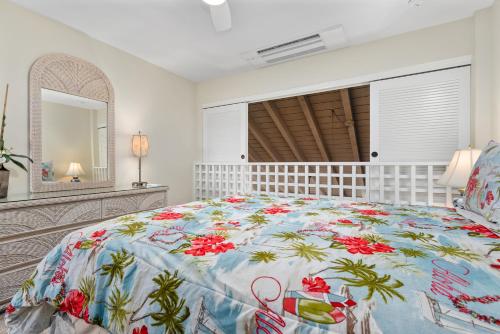 um quarto com uma cama grande e uma colcha floral em Maui Kamaole L209 - MCH em Kihei