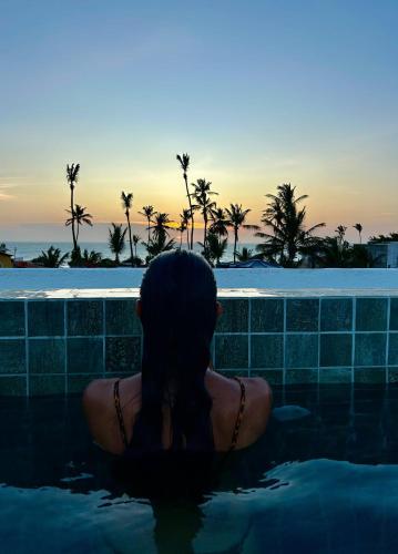 a woman sitting in a swimming pool watching the sunset at Pousada Baobá in Jericoacoara