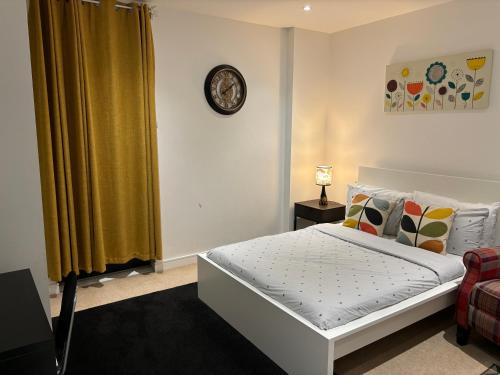 1 dormitorio con 1 cama y reloj en la pared en Modern en-suite room and self catering in london en Woolwich