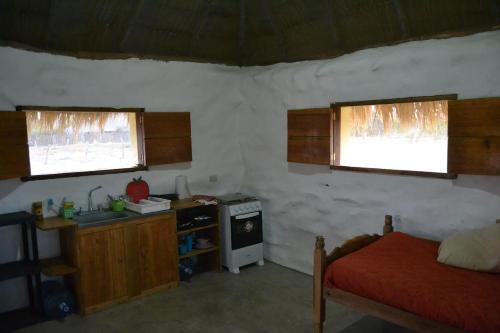 um quarto com uma cozinha, uma cama e 2 janelas em Castaways Nicaragua em Popoyo