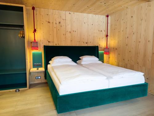 a large bed in a room with wooden walls at SportLodge MOUNTAIN SUITE - Alpine Apartment with Shared Pool, Whirlpool & Sauna, presented by AlpenLuxus in Kleinboden