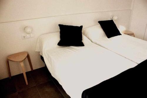 two beds in a room with white sheets and black pillows at OD'A Apartaments in Roses