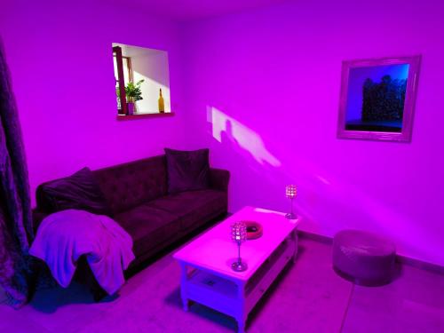 Sala de estar de color rosa con sofá y mesa en Les Secrets d'Amandine en Troguéry