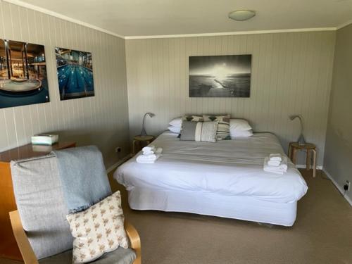 a bedroom with a large bed and a chair at The Pacific Room, Tapeka Point in Russell