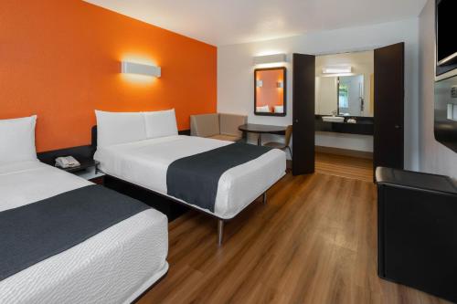 een hotelkamer met 2 bedden en een oranje muur bij Studio 6 Suites Carpinteria, CA Santa Barbara South in Carpinteria