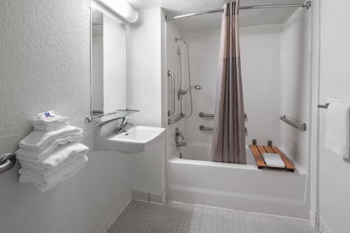 a white bathroom with a sink and a shower at Studio 6 Suites Carpinteria, CA Santa Barbara South in Carpinteria