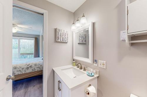 Baño blanco con lavabo y espejo en Misty Harbor Beach Retreat, en Gilford