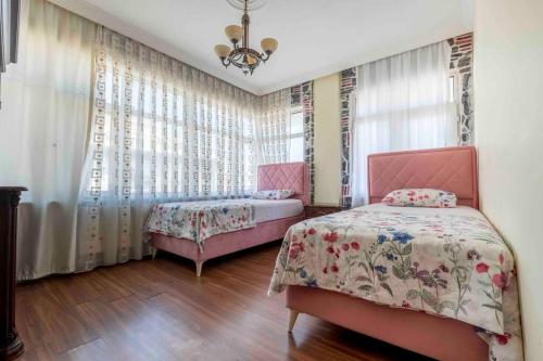 a bedroom with two beds and curtains and a chandelier at Bakırköy'de ailecek konaklayabilceginiz daire in Istanbul