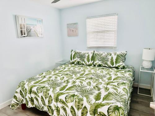 a bedroom with a bed with a green and white comforter at Beachfront Bungalow in Clearwater Beach