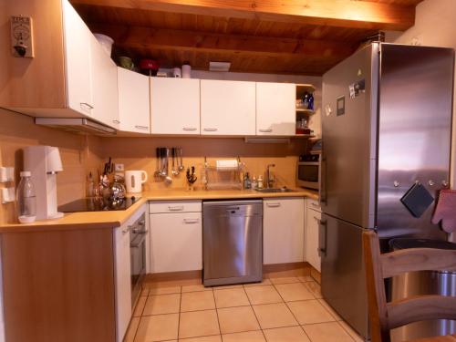 La cuisine est équipée de placards blancs et d'un réfrigérateur en acier inoxydable. dans l'établissement Tignes les Brévières - Chalet Chardonnay, à Tignes