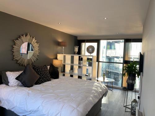 シェフィールドにあるDeluxe City Centre Studio Apartment with Balcony & City Views - FREE WIFI NETFLIX, GYM ACCESS - WESTONEのベッドルーム(白いベッド1台、鏡付)