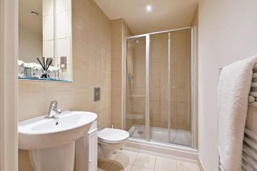 La salle de bains est pourvue de toilettes, d'un lavabo et d'une douche. dans l'établissement Deluxe City Centre Studio Apartment with Balcony & City Views - FREE WIFI NETFLIX, GYM ACCESS - WESTONE, à Sheffield