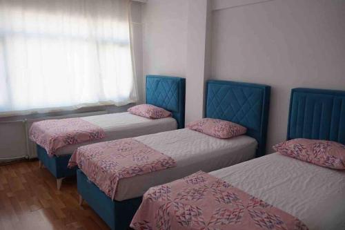 伊斯坦堡的住宿－Bakırköy'de ekonomik daire，客房设有三张床、粉色床单和窗户。