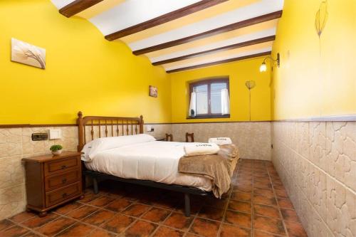 1 dormitorio con cama y pared amarilla en ETXEORDEKOA. Apartamento con encanto en Plena Naturaleza, en Aia
