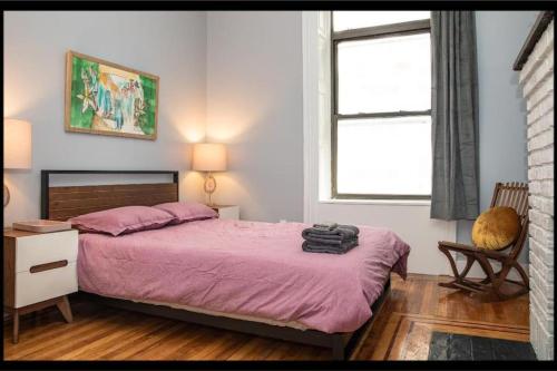 a bedroom with a bed with a purple blanket and a window at 3BR Central Park in New York