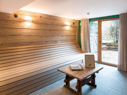 a room with a wooden wall with a wooden table at SportLodge GOLF SUITE - Cozy Apartment with Shared Pool, Whirlpool & Sauna, presented by AlpenLuxus in Kleinboden