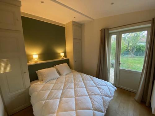 1 dormitorio con cama grande y ventana grande en La Sellerie du Figuier, en Charentay