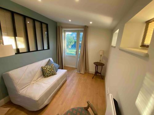 sala de estar con sofá blanco y ventana en La Sellerie du Figuier, en Charentay