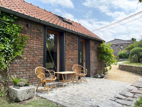 Cette maison en briques dispose d'une terrasse avec une table et des chaises. dans l'établissement Bayda's Tiny House, à Sprimont