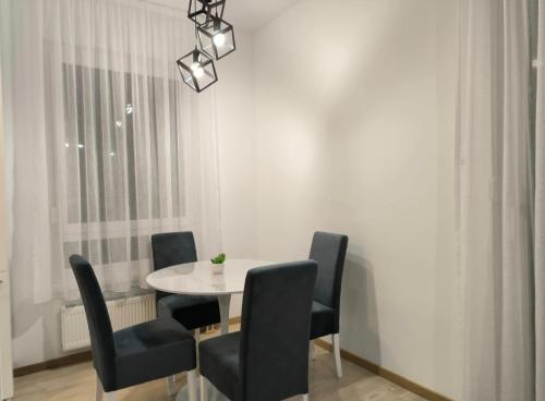 a dining room with a white table and black chairs at Apartman Kosmos in Banja Luka
