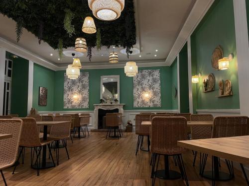 um restaurante com paredes verdes, mesas e cadeiras em L'Harmony em Saint-Arnoult-en-Yvelines