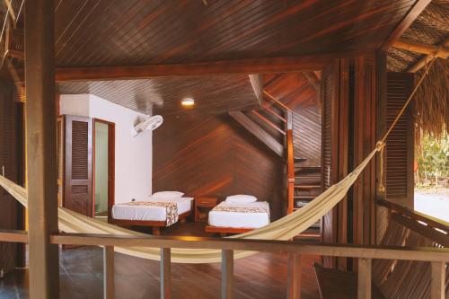 two beds in a room with a hammock at Cabañas Tequendama - Parque Tayrona in El Zaino