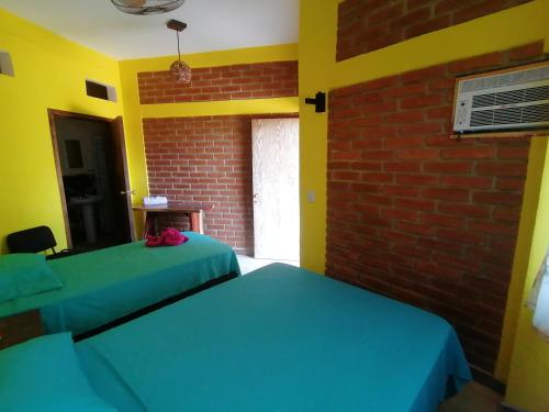 two beds in a room with a brick wall at HOTEL AVE FENIX in Mazunte