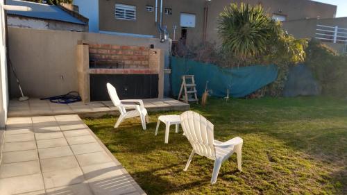 two white chairs sitting in the grass in a yard at Casa Amoblada p/ Alquiler Temporario - Bahía Blanca in Bahía Blanca