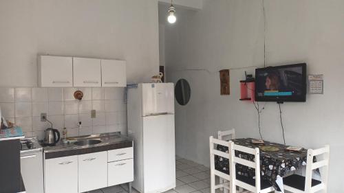 uma cozinha com um frigorífico e uma televisão na parede em Kitnet em Tramandaí