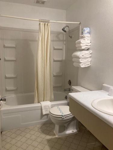 a bathroom with a toilet and a tub and a sink at Travelodge by Wyndham Canyonville in Canyonville