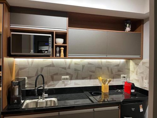 eine Küche mit einer Spüle und einer Mikrowelle in der Unterkunft Studio 201 SP Moema Super Equipado in São Paulo