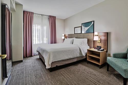 a hotel room with a bed and a chair at Staybridge Suites - Albuquerque Airport, an IHG Hotel in Albuquerque