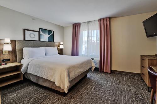 a hotel room with a bed and a television at Staybridge Suites - Albuquerque Airport by IHG in Albuquerque