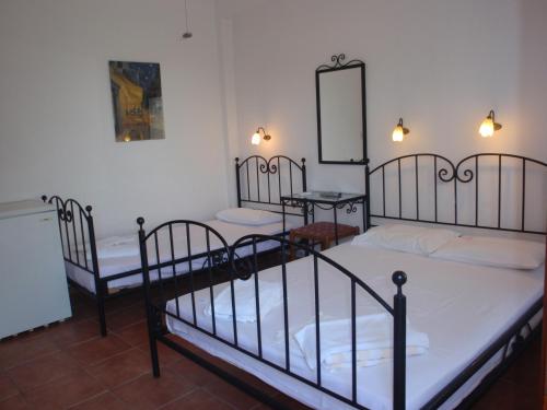 a room with three beds and a mirror at Petrouda's Apartments in Samothráki