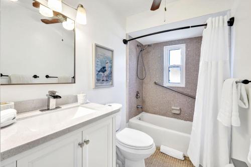 a white bathroom with a sink and a toilet at Beach Daze - Summer Sale! Southern Facing Pool, Walk To The Beach - No Ian Damage! in Naples