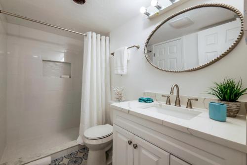 a bathroom with a sink and a toilet and a mirror at FALL SPECIAL! Seas The Day - This one has it all - Walk to Vanderbilt beach! in Naples
