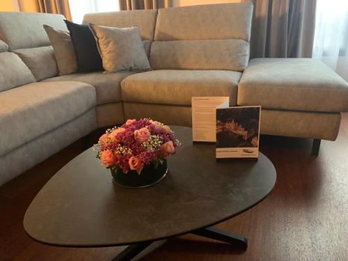 a living room with a couch and a table with flowers at Botanique Suites AirBnB, Antwerp in Antwerp
