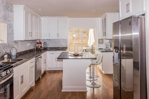 a kitchen with white cabinets and a stainless steel refrigerator at Unique cabin, 10 minutes from downtown in Kansas City