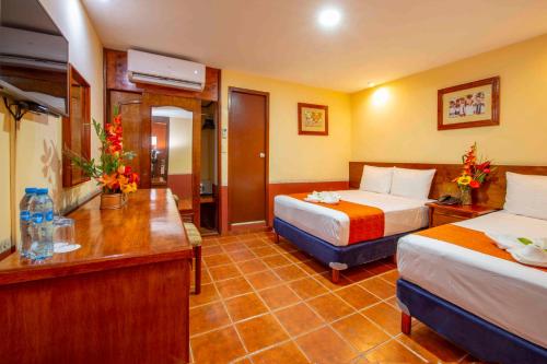 a hotel room with two beds and a desk at Hotel del Gobernador in Mérida