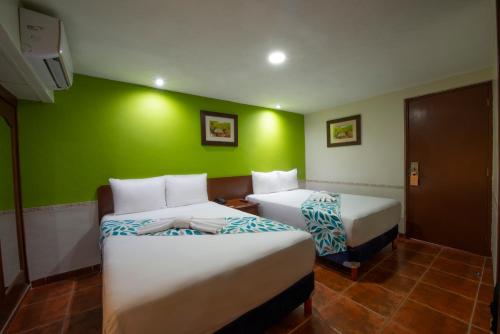 a room with two beds and a green wall at Hotel del Gobernador in Mérida