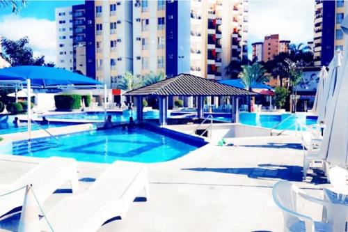 uma piscina com cadeiras brancas e um edifício em Eldorado Thermas Park frente ao parque aquático em Caldas Novas